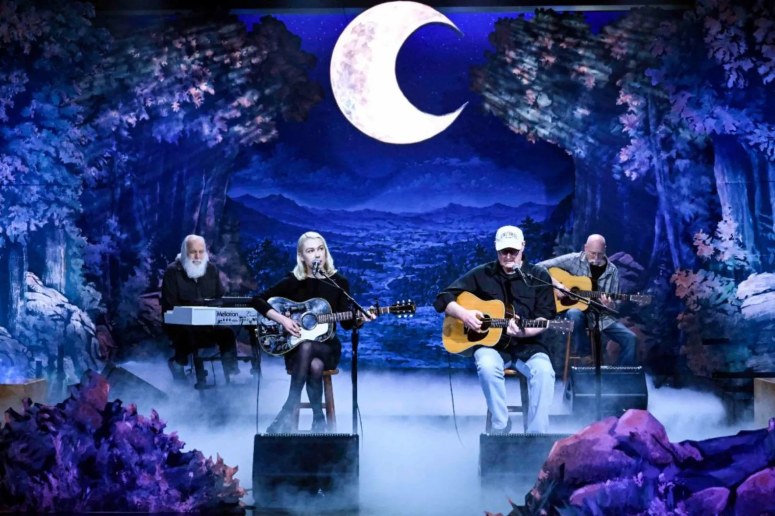 Phoebe Bridgers performing on stage with her band